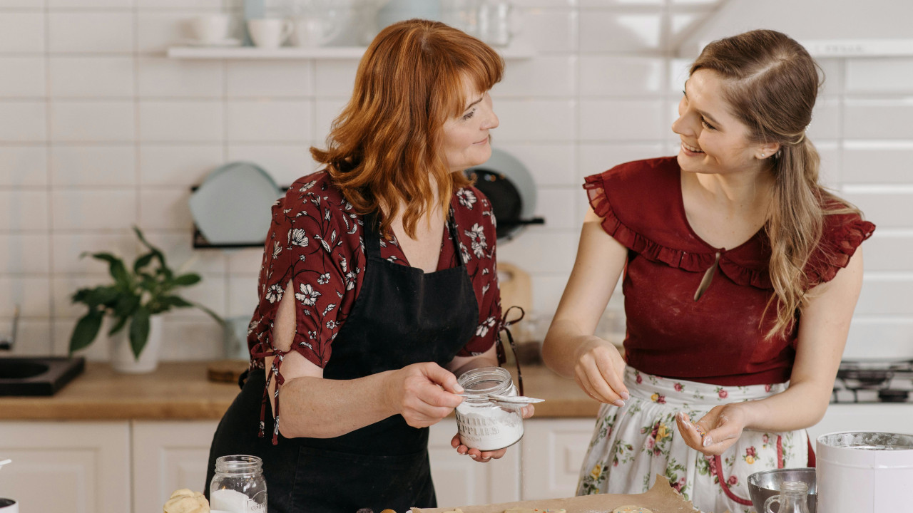 Мама с дочкой на кухне разговаривают смеясь, во время приготовления пищи