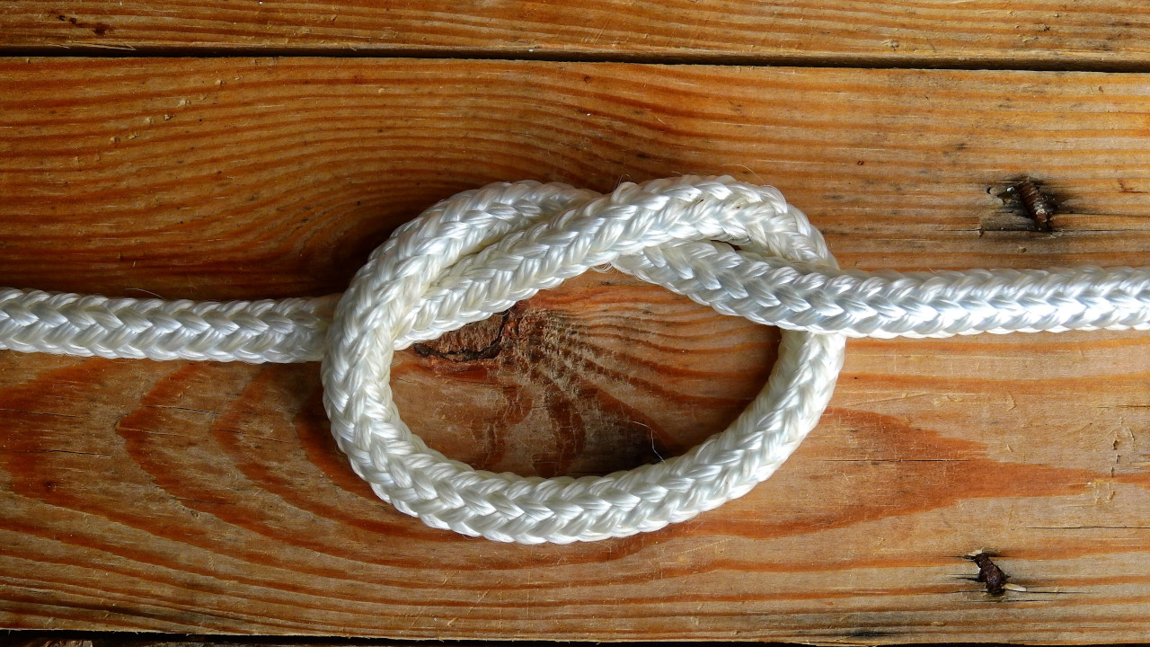 Полимерный шнур белого цвета, завязан лёгким узлом