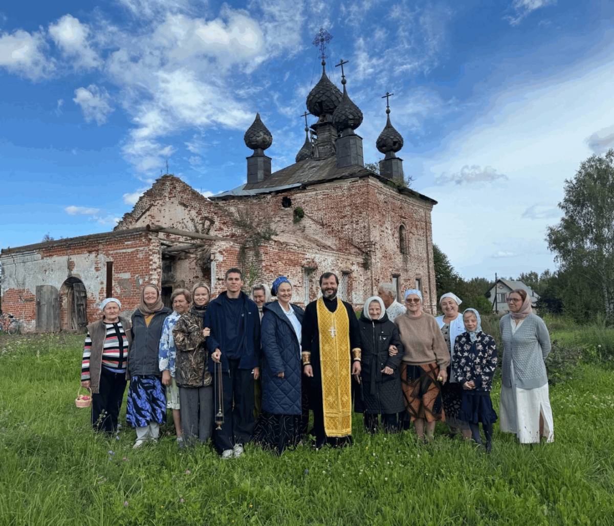 Люди во лаве со священником на фоне восстанавливаемого храма
