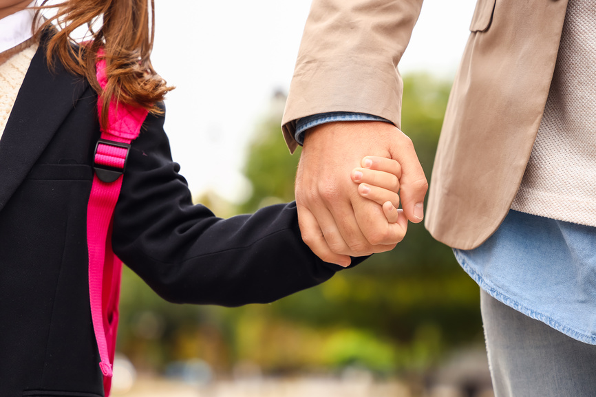 Мужчина ведет свою маленькую дочь в школу, крупным планом