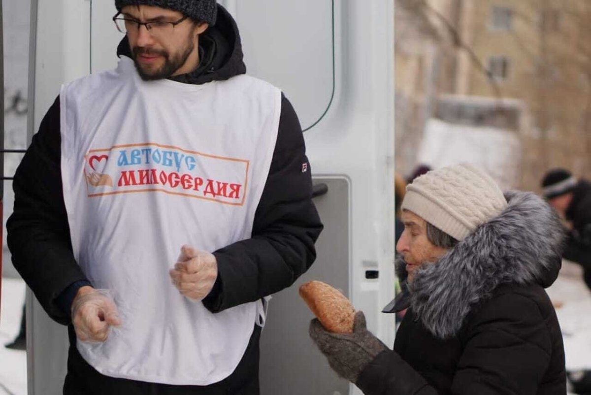 Волонтер передает хлеб бабушке