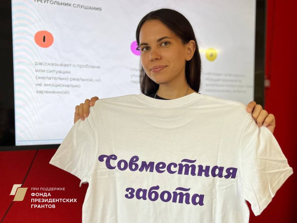 Девушка держит в руках футболку с надписью «Совместная забота»