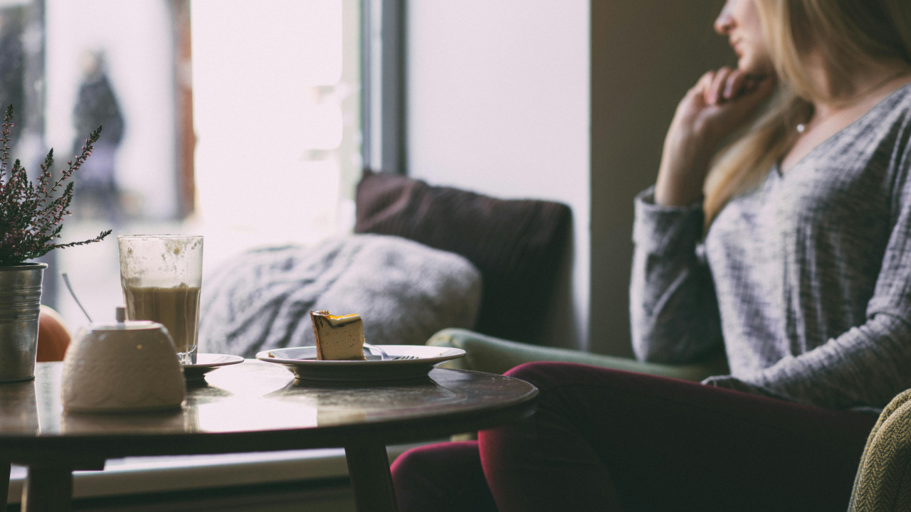 Девушка в кафе смотрит задумчиво в окно