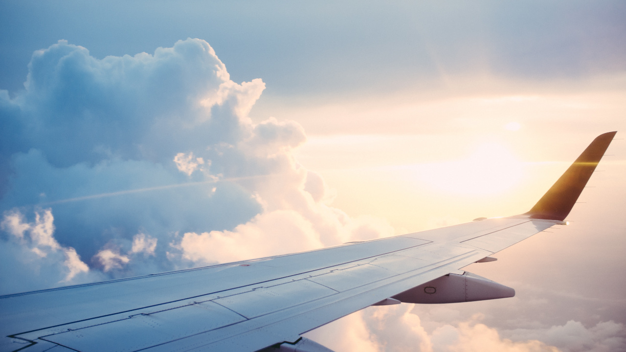 Крыло самолёта на фоне солнца и облаков