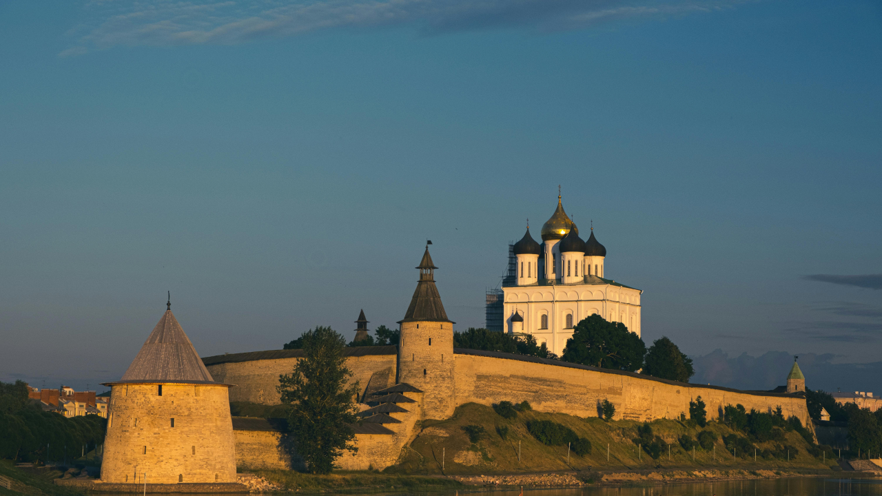 Белокаменный храм на берегу реки за каменной стеной