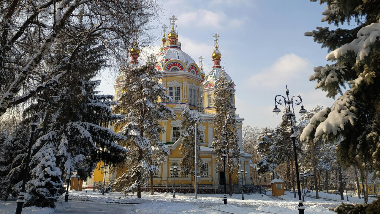 Заснеженный сквер с красивым храмом в лучах утреннего солнца