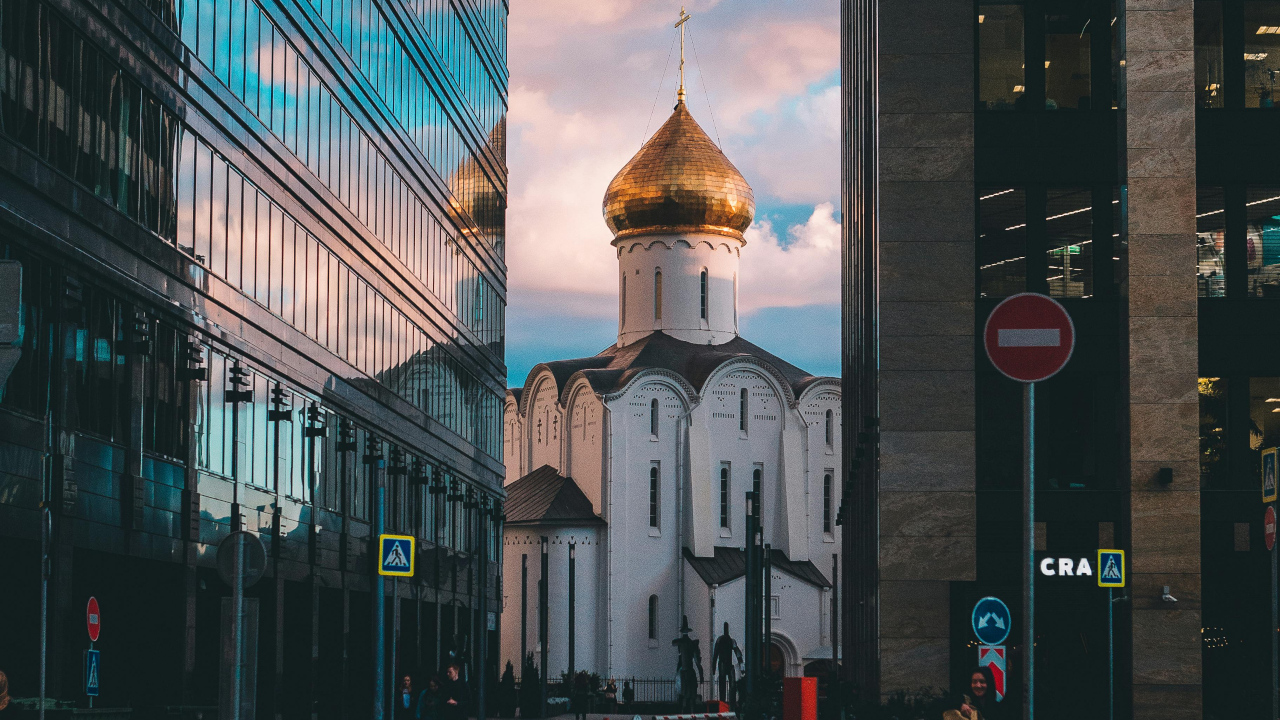 Белокаменный храм с золотой маковкой виднеется между высотками