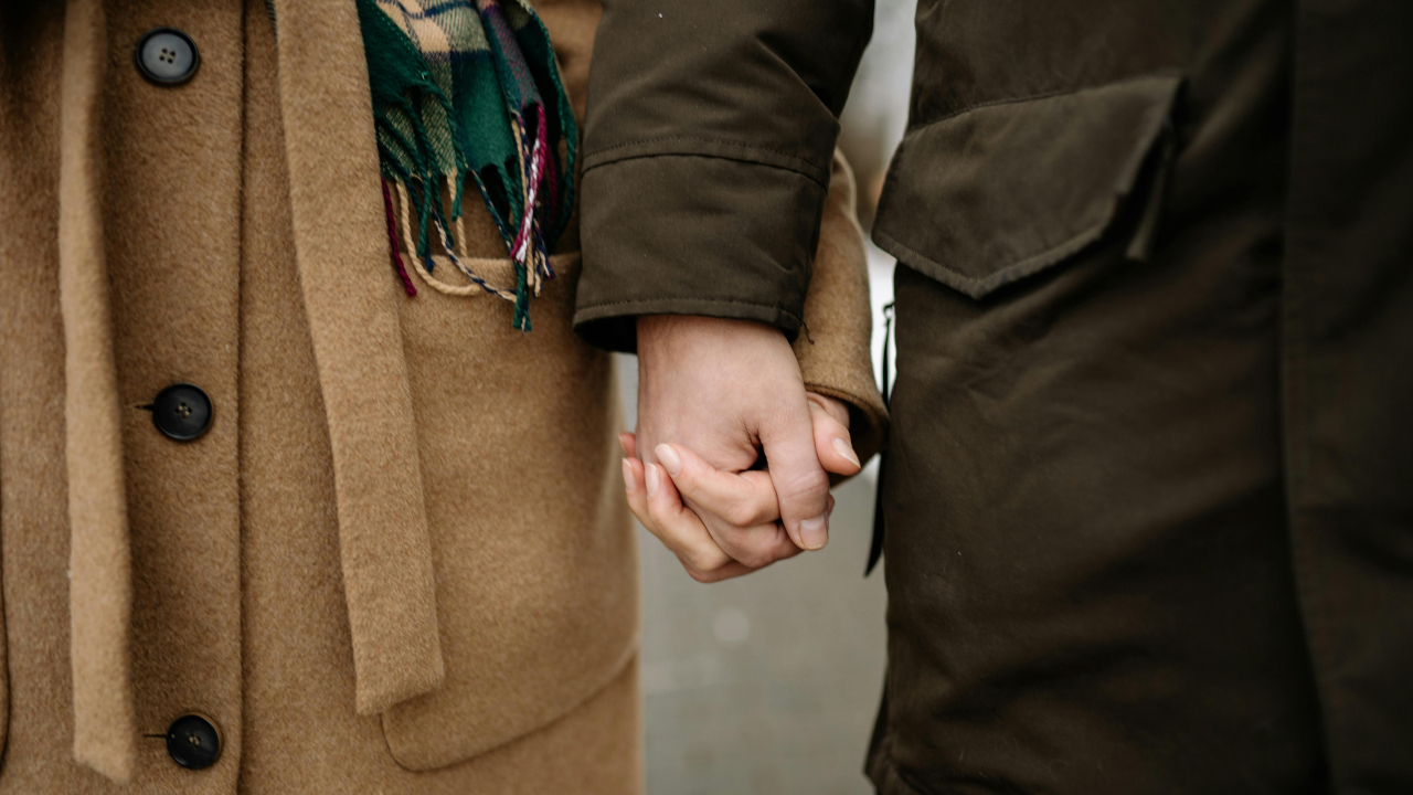 Мужчина держит женщину за руку